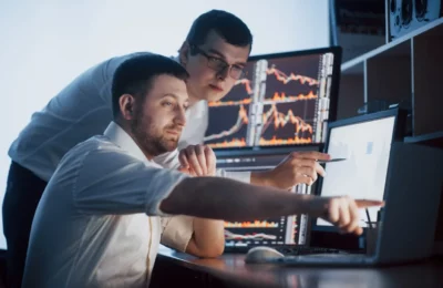 dicas-de-investimentos-2-homens-bem-sucedidos-apontando-computdor-com-graficos-de-investimentos