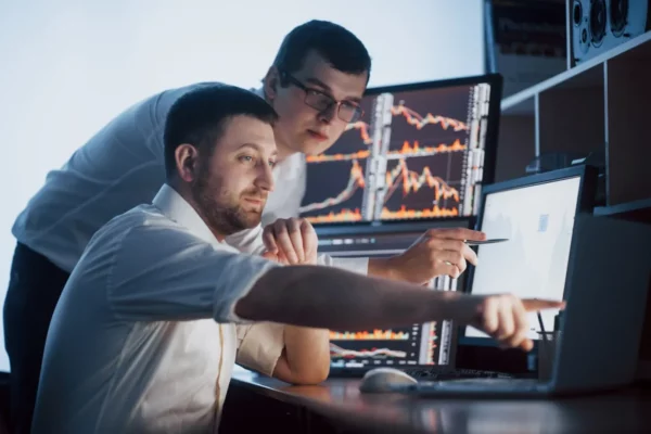 dicas-de-investimentos-2-homens-bem-sucedidos-apontando-computdor-com-graficos-de-investimentos