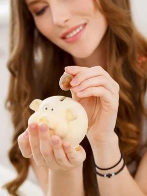 garota-atraente-guardando-money dinheiro moeda em um porquinho investimento dividendos proventos rendimentos longo prazo acumular patrimonio vertical