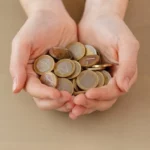 maos cheias de moedas representa dividendos rendimentos investimentos longo prazo renda fixa vertical