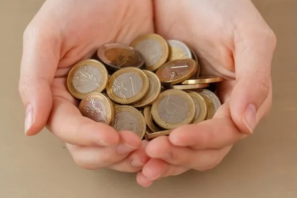 maos cheias de moedas representa dividendos rendimentos investimentos longo prazo renda fixa vertical