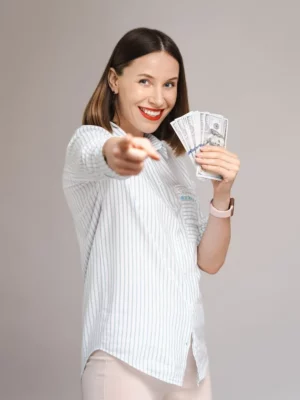 mulher sorrindo apontando para você e com dinheiro na outra mão como ganhar dinheiro vertical