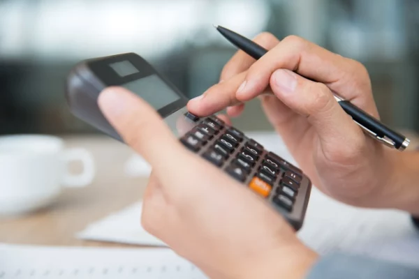 pessoa digitando na calculadora renda fixa e renda variável qual o melhor finanças e investimentos